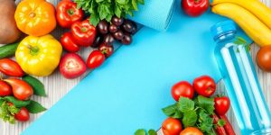 Colorful fruits and vegetables with a yoga mat and water bottle.